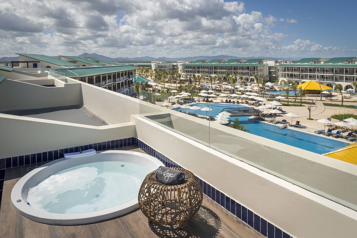 Un espace piscine aménagé sur le toit, avec un jacuzzi, des chaises longues et une vue sur un complexe hôtelier.