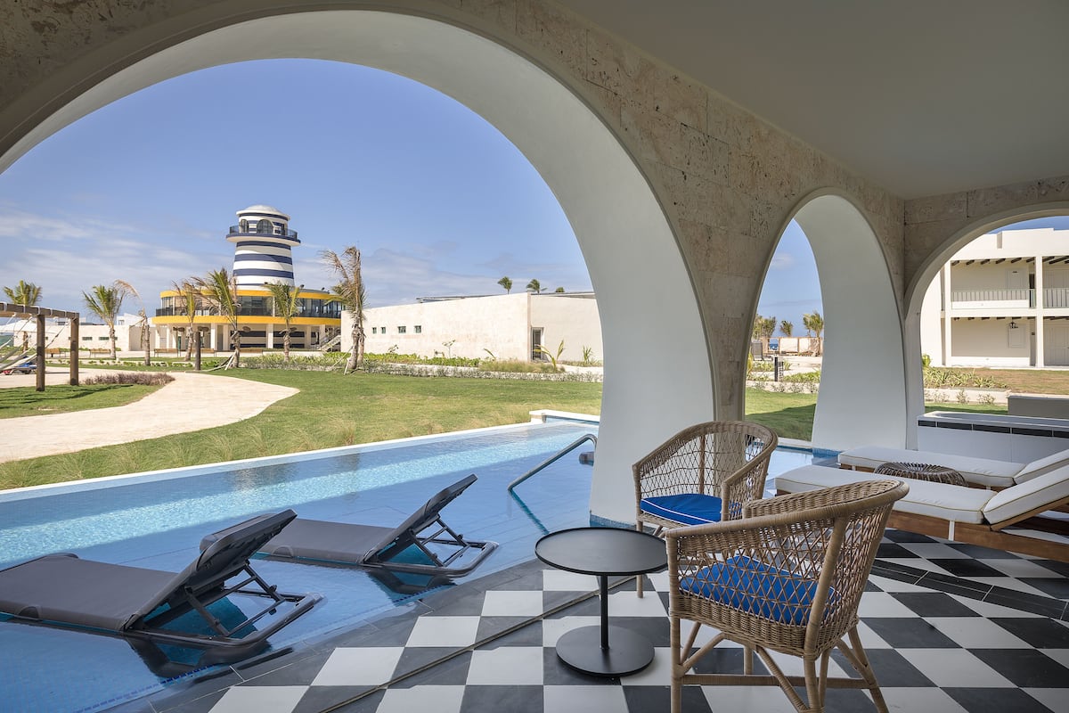 Un espace piscine avec des chaises longues et une vue sur un phare.