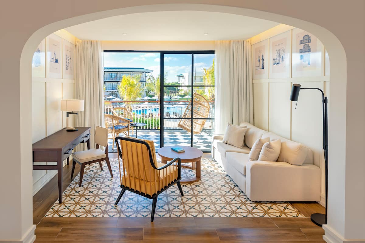 Une chambre d’hôtel moderne dotée d’un balcon, d’un canapé, d’une table à manger et d’une chaise.