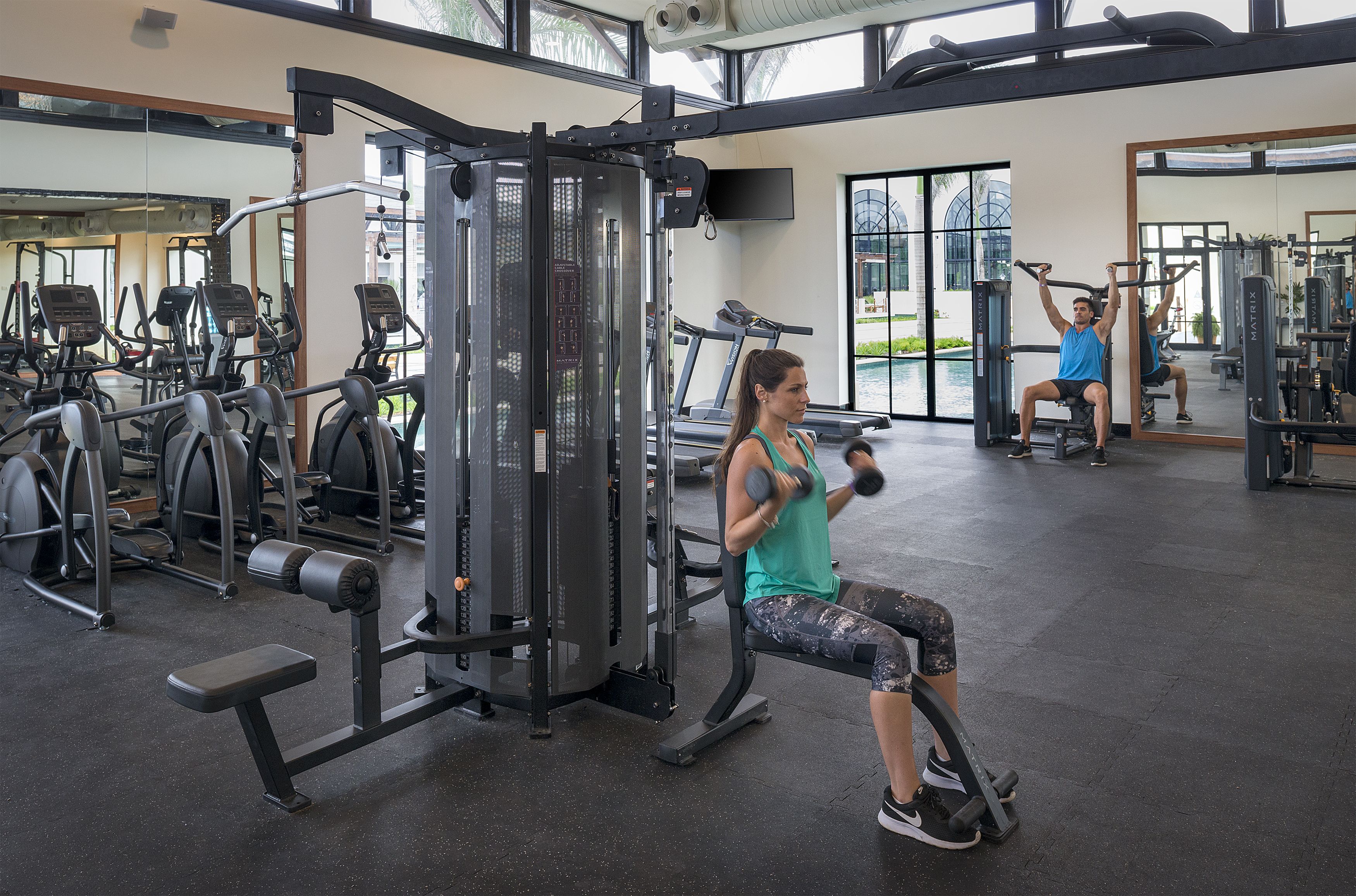 A gym with various exercise equipment, including a bench press, a squat rack, and a treadmill.