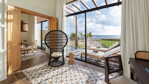 Varanda ampla com vista para o mar, equipada com cadeira, mesa pequena e sofá.