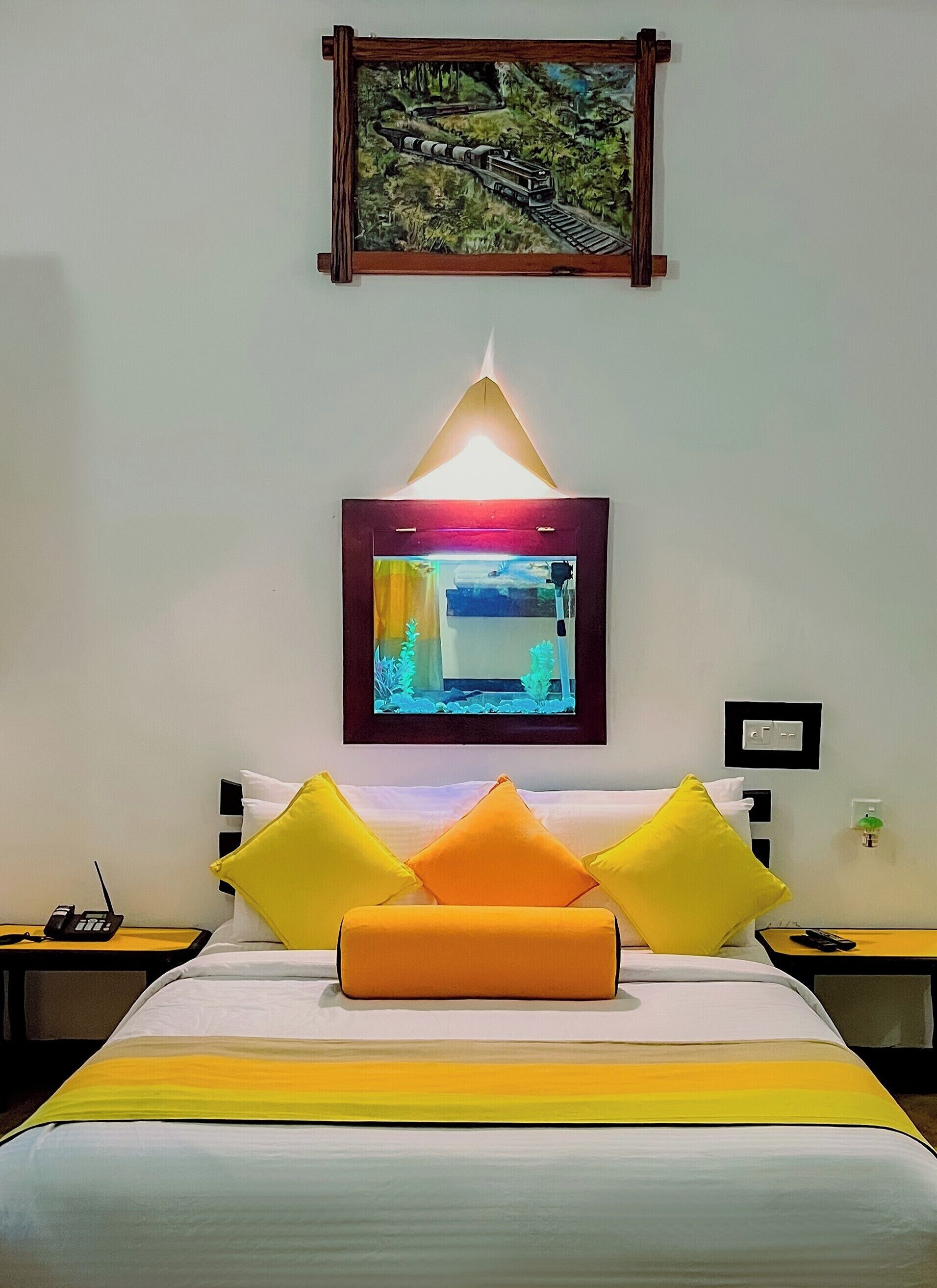 Una habitación de hotel con una cama, una mesita de noche, una lámpara, un cuadro y un televisor.