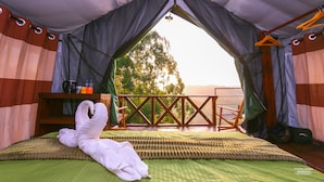 Una habitación con carpa, una cama, una silla de madera y vistas a árboles.