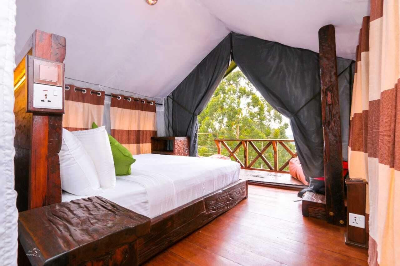 Een slaapkamer met een houten bed, een klein nachtkastje, een stopcontact en een raam met gordijnen.