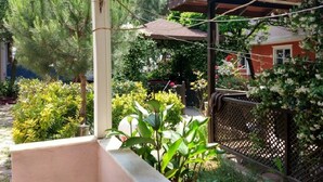A covered outdoor area with a pergola, plants, and a view of a building. - Deniz Kizi Otel (Armutlu)