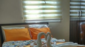 A bed with an orange bedspread, white pillows, and a white headboard. - Deniz Kizi Otel (Armutlu)