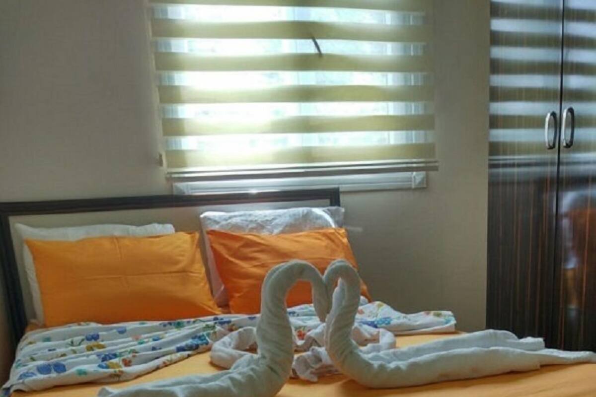 A bed with an orange bedspread, white pillows, and a white headboard.