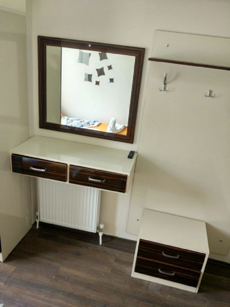 A room with a built-in desk, a mirror, a radiator, and a wardrobe.
