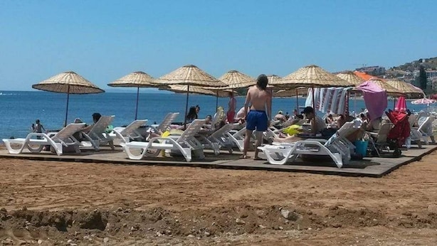 A beach with sun loungers and umbrellas, a clear sky, and a view of the sea. - Deniz Kizi Otel (Armutlu)
