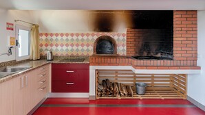 Una cocina con horno de ladrillo, armarios rojos y salpicadero de azulejos.