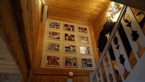 Een houten interieur met een trap en een wand vol ingelijste foto's.
