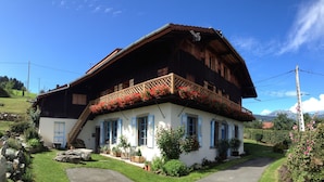 Een klassiek chalet met een houten gevel, een balkon met een lattenleuningen en een pad van stenen dat naar de ingang leidt.