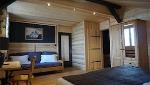 Een gezellige kamer met een bed, een bank en een houten garderobe.