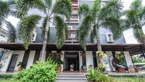 Un edificio moderno con entrada cubierta, palmeras y plantas en macetas.