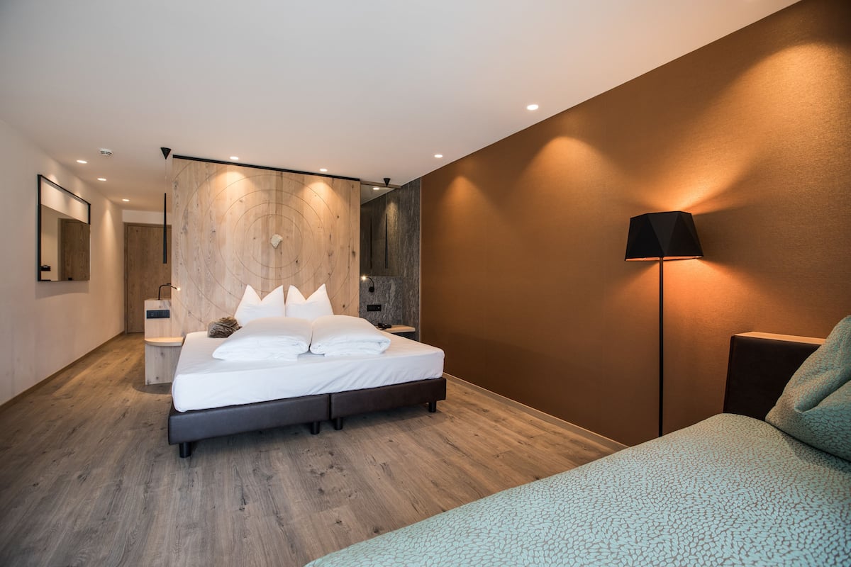 Un dormitorio moderno con cama, mesita de noche, lámpara y un muro decorativo de madera.