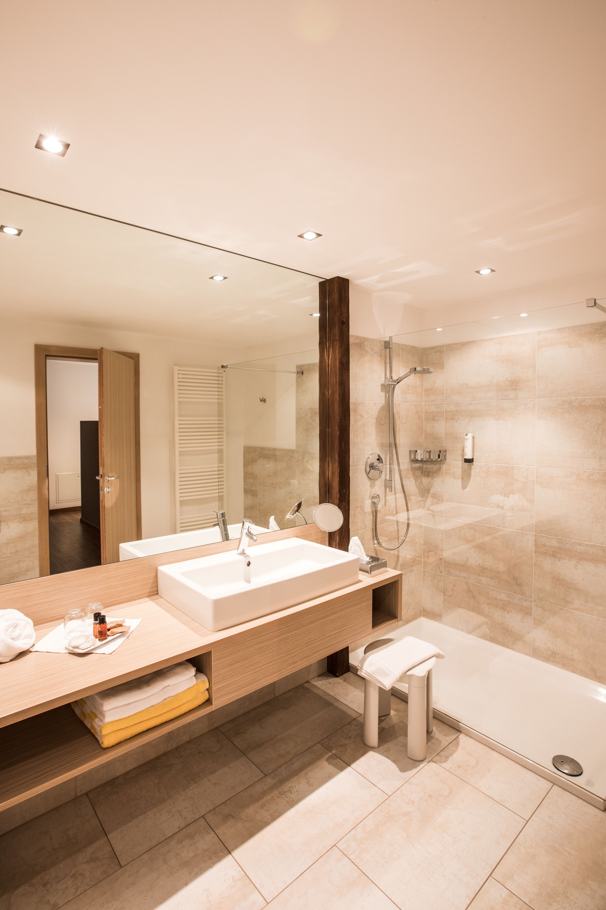 A modern bathroom with a dual sink vanity, a glass-enclosed shower, and a large mirror.