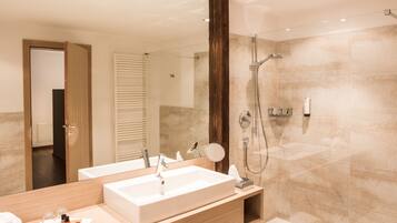 A modern bathroom with a dual sink vanity, a glass-enclosed shower, and a large mirror.