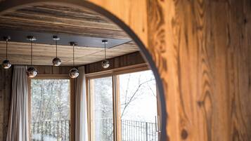 Un interior de madera con ventanal circular, techo de madera y lámparas colgantes.