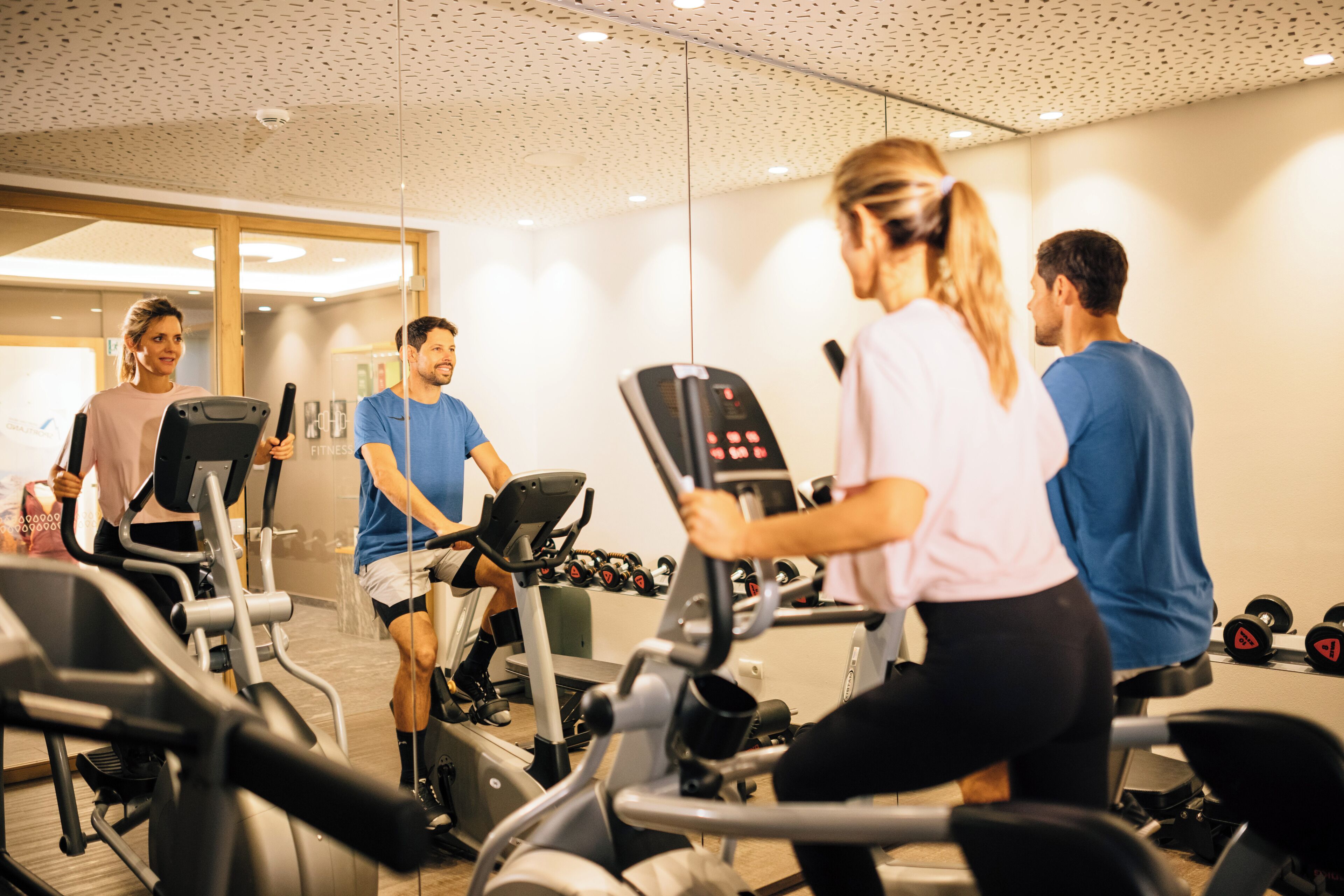 Un gimnasio con cintas de correr, elípticas y mancuernas.