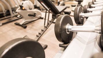 A gym with rows of exercise equipment including treadmills, ellipticals, and weight machines.