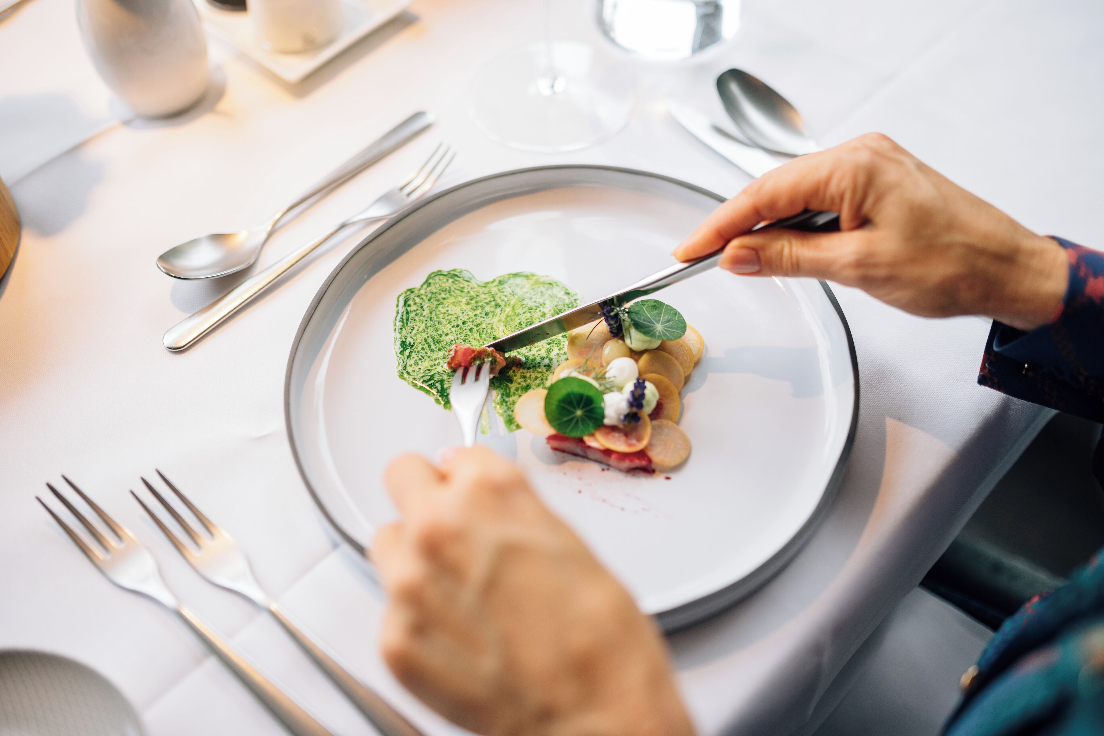 A dining table with a plate of food, utensils, and a glass of water.