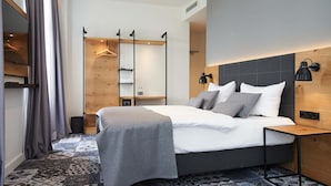 Una habitación de hotel moderna con una cama grande, lámparas de noche, un cabecero de madera y un suelo con diseño.