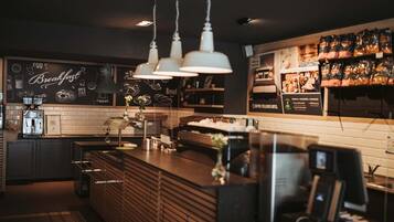 A coffee shop interior with a counter, coffee machines, and a chalkboard menu.