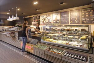 Una vitrina de panadería con diversos productos horneados y un mostrador con un menú.