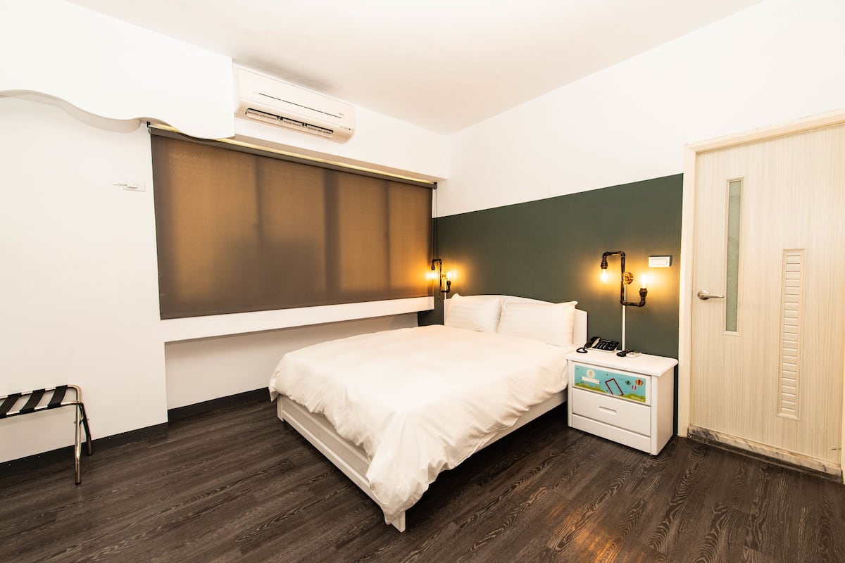 Un dormitorio con cama, mesita de noche y puerta.