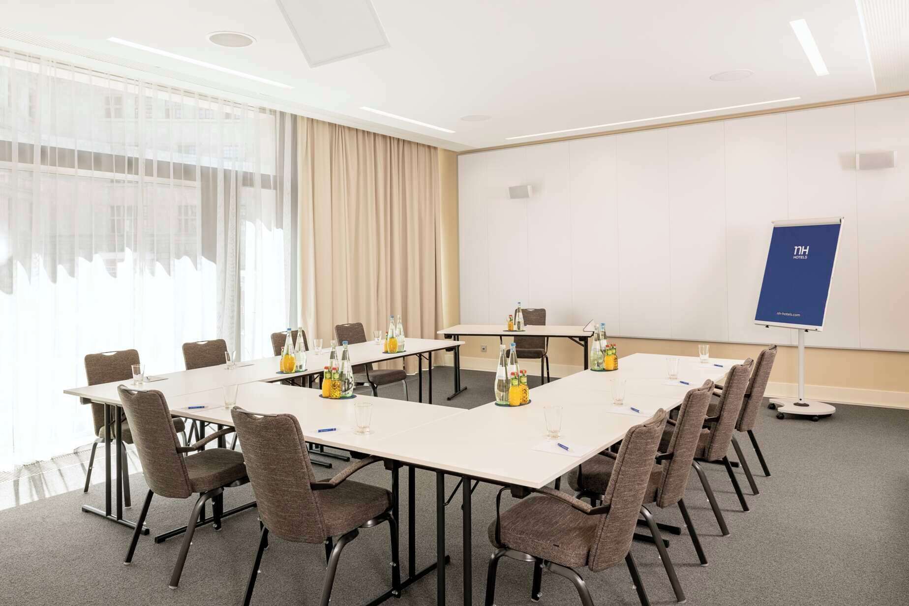 Ein Konferenzraum mit langem Tisch, Stühlen und einer Projektionsleinwand.