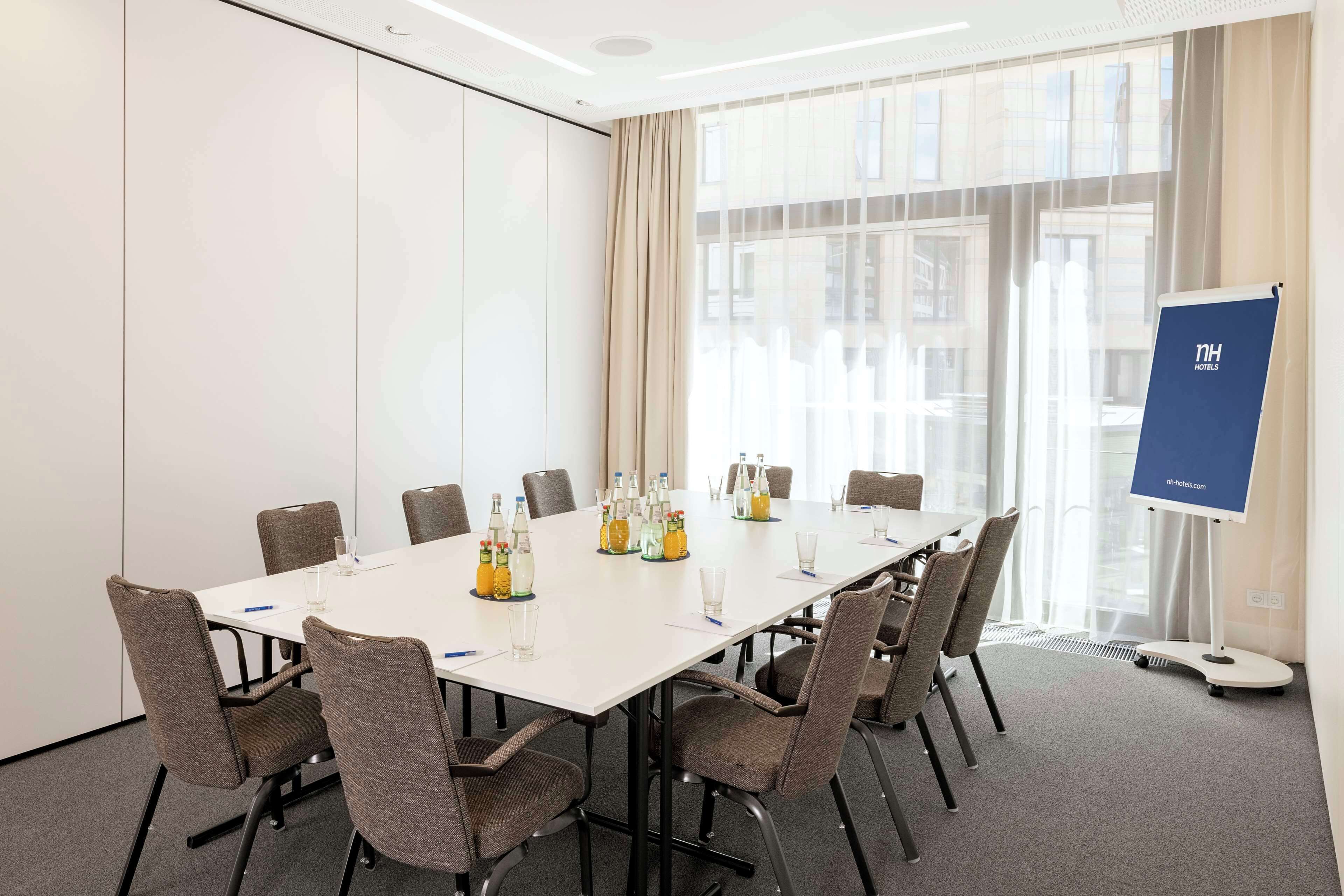 Ein Konferenzraum mit einem langen Tisch, Stühlen und einer Projektionsleinwand.