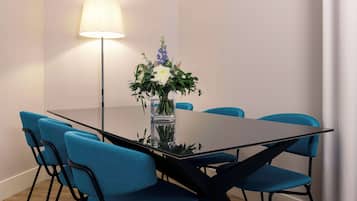 Uma mesa de conferência com um vaso de flores, cadeiras azuis e um abajur.