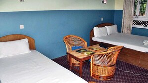 Una habitación con dos camas, una mesa y dos sillas de mimbre.
