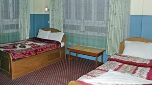 Habitación con dos camas, una mesita y cortinas.