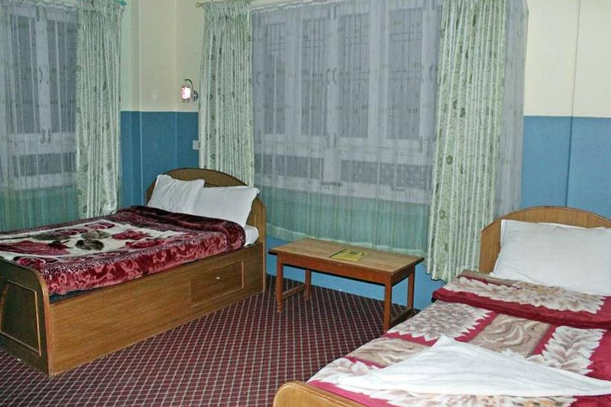 A room with two beds, a small table, and curtains.