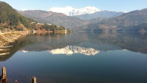 Un lago tranquilo con una cadena montañosa al fondo y un pequeño asentamiento a la izquierda.