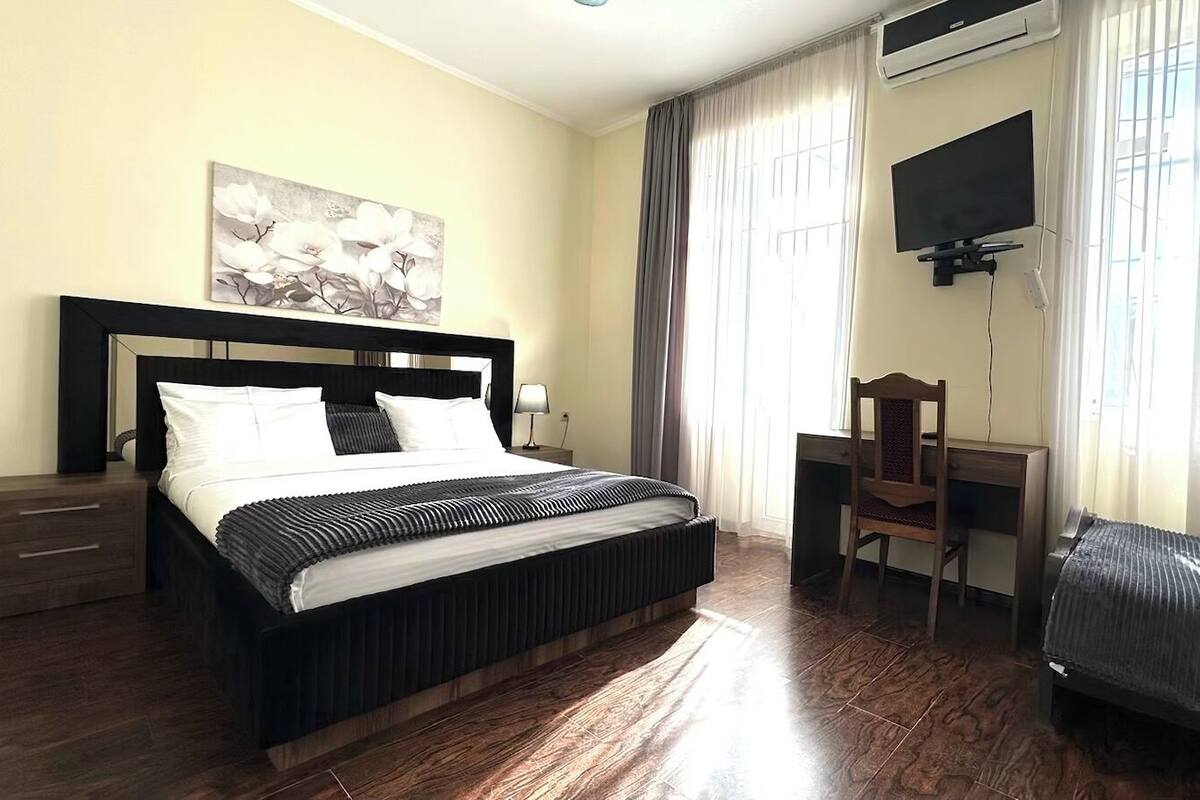 A hotel room with a bed, a desk, a chair, and a TV.