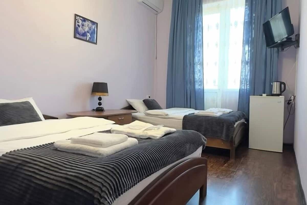 A hotel room with two beds, a desk, a television, and a coffee maker.