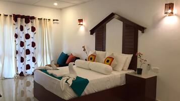 A modern hotel room with a large bed, a nightstand, a wall-mounted light, and a window with curtains.