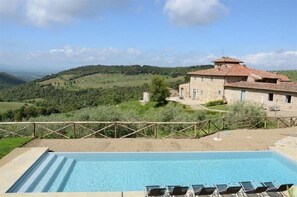 Una piscina al aire libre, sillones reclinables de piscina