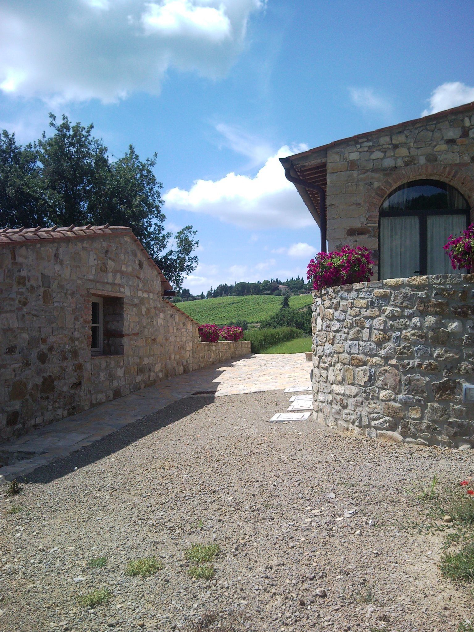 A stone building with a gravel path leading to a green landscape.