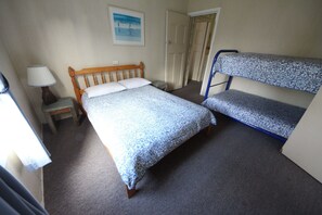 Cozy retreat with a single bed and matching bunk bed, featuring a bedside table and lamp.