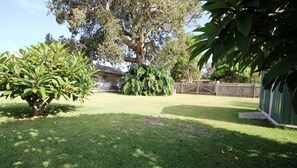 Enjoy the serene atmosphere of this beautifully maintained backyard with lush greenery and a wooden fence.