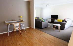 Relax in this stylish living room with a sofa, desk, and flat-screen TV.
