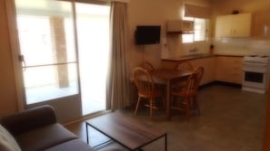 Cozy space with a dining area, kitchenette, and seating area, featuring a TV and large windows.