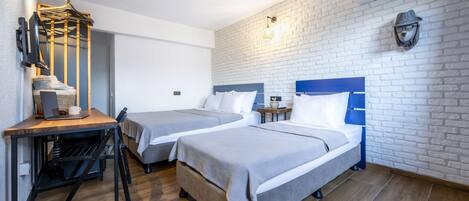 A room with two beds, a desk, and a hanging coat rack.