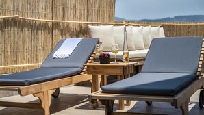 Two lounge chairs with cushions, a small wooden table with a glass of wine and a bowl of fruit, and a bamboo fence in the background. - The Poyz Hotel Bodrum (Bodrum)