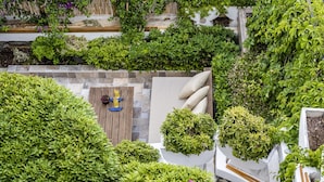 A rooftop garden with a seating area, lush greenery, and a stone wall. - The Poyz Hotel Bodrum (Bodrum)