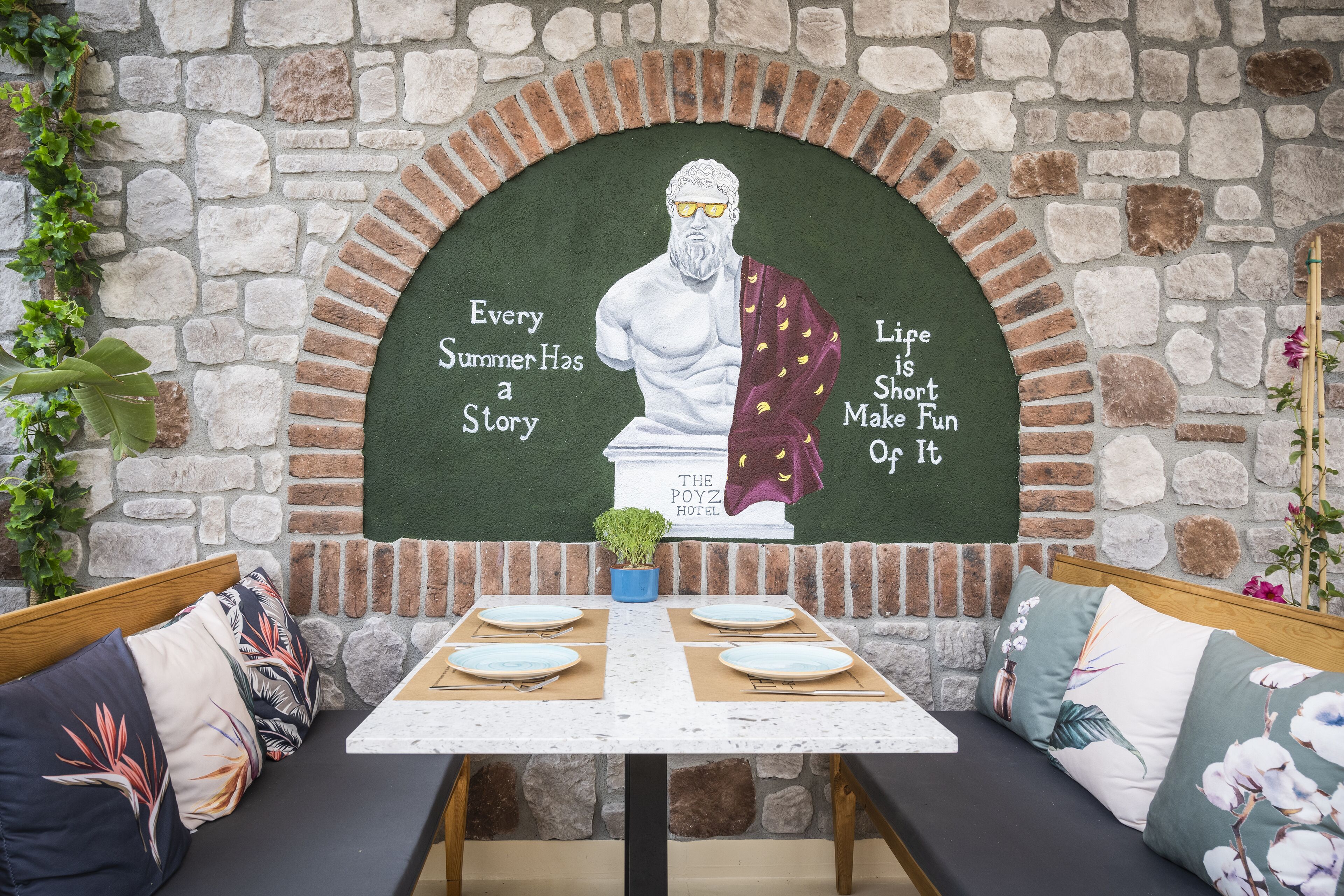 Un restaurant dont le décor est agrémenté d’un mur en pierre, d’une fresque murale et d’une table dressée pour quatre personnes.