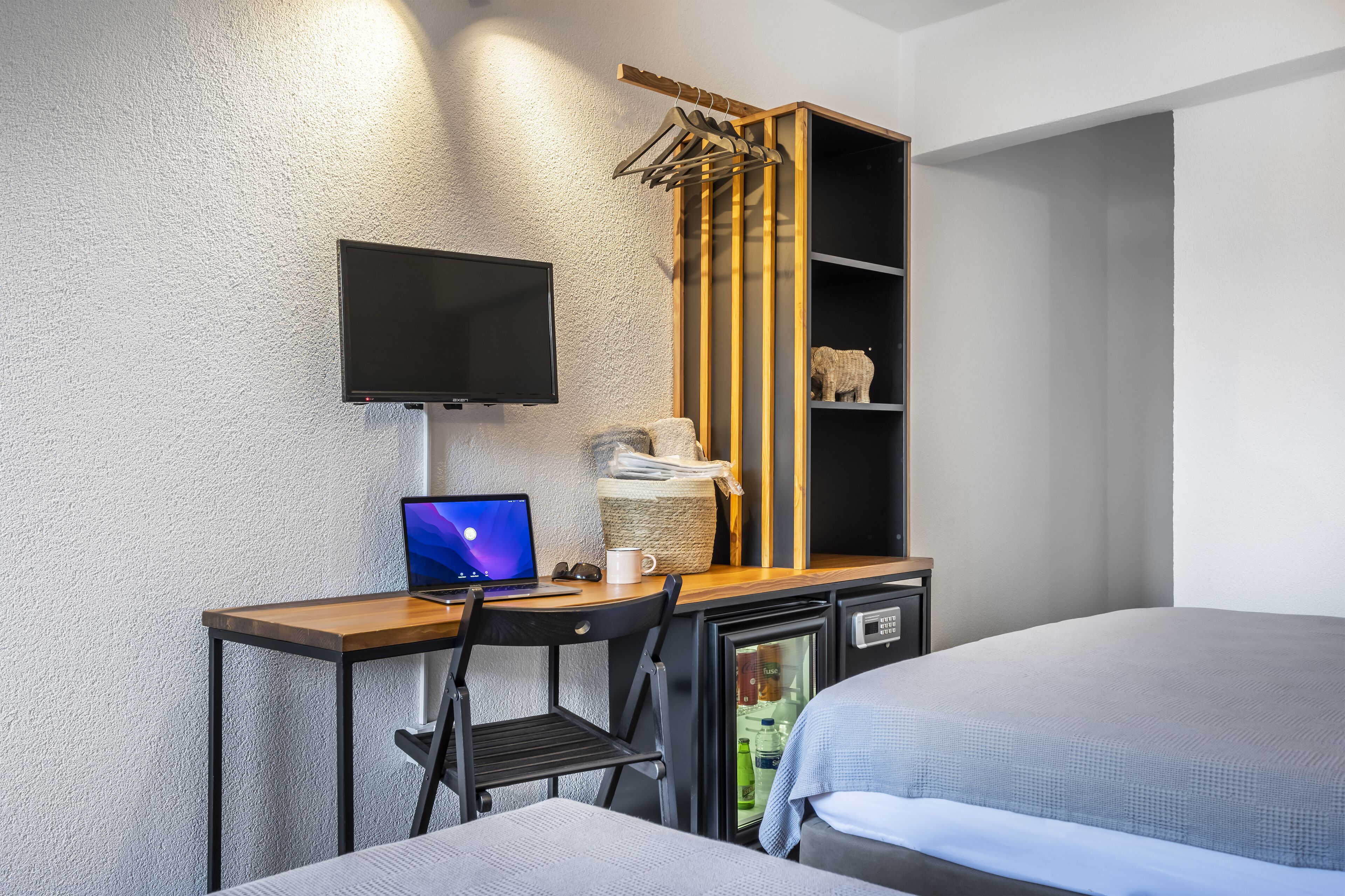 A compact hotel room with a desk, a television, a small refrigerator, and a bed.